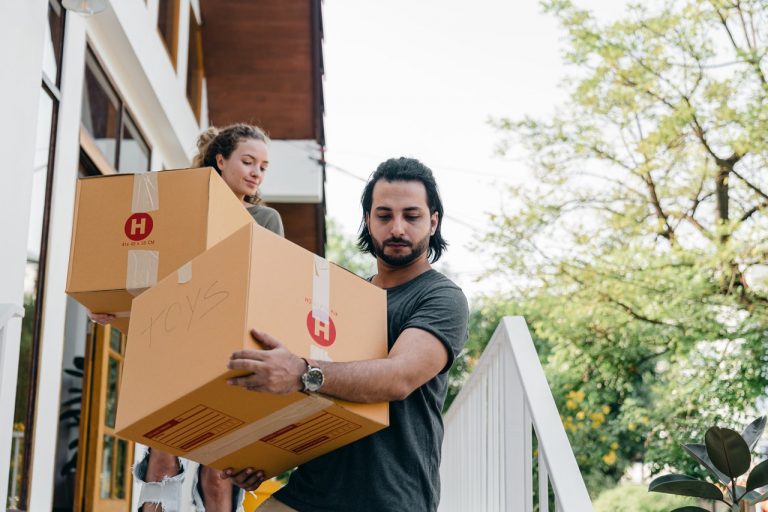 couple-carrying-boxes-on-steps-while-moving-out-of-house-4246272